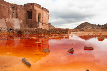 Mazzarron abandoned mine with vivid red and orange coloured contaminated pool in front of old mine...