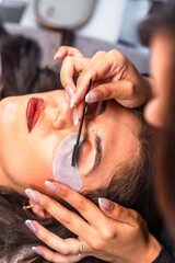 Fototapeta premium Beautician applying eyelash extensions on client in beauty salon