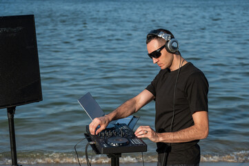 Caucasian man works as a DJ on the beach. 