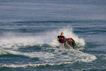 Young man rides a jet ski across turquoise waters during seaside vacation. Concept water sports...
