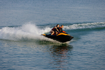 Fototapeta premium Happy couple speeding across the water on a jet ski. Concept energy, freedom, and bonding.