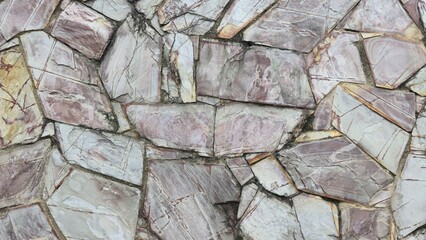 Large stone wall, fence designed with many stones, small and large square and triangle stones connected together, texture and background image of the wall.