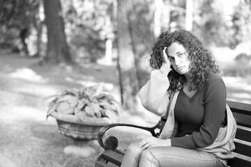 Homeless woman on bench in park, space for text. Black and white effect