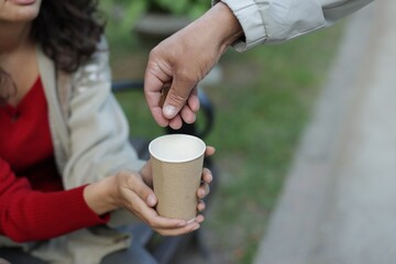 Man giving money to homeless people outdoors, closeup. Space for text