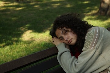 Poor homeless woman on bench in park