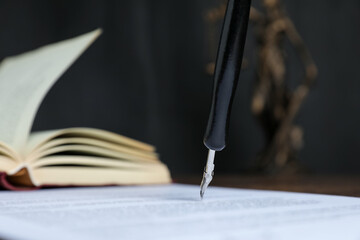 Signing notary document with fountain pen at table against black background, closeup