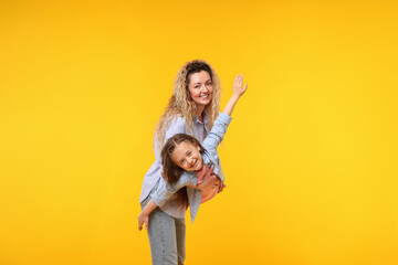 Family. Happy mother and her daughter on yellow background