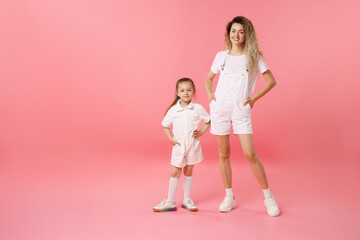 Family. Happy mother and her daughter posing on pink background. Space for text