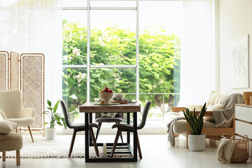 Wooden table, chairs, sofa and decor in dining room. Interior design