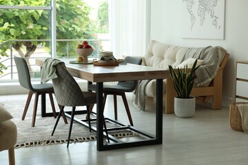 Wooden table, chairs, sofa and decor in dining room. Interior design