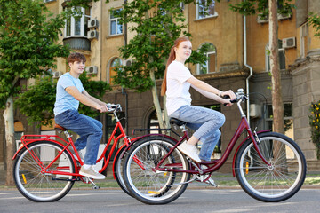 Fototapeta premium Teenage girl and boy riding bicycles on city street
