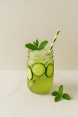 cucumber mint detox jam jar cocktail on marble with paper straw and fresh herbs and space for text concept of wellness drink clean lifestyle visual