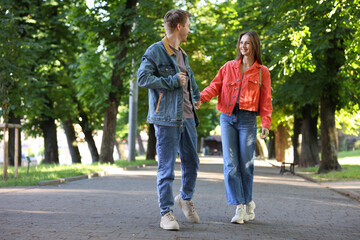 Lovely couple walking together in park, space for text