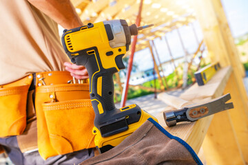 Construction Worker Using a Power Drill at a Building Site During Daylight Hours
