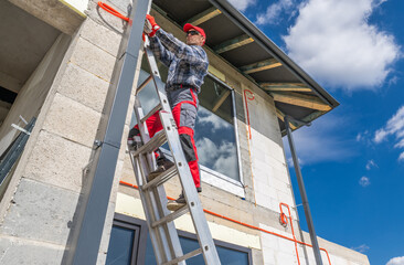 Worker Climbs Ladder to Install Equipment on Construction Site During Sunny Day