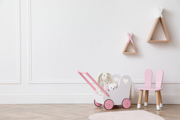 Child's toys, chair and wigwam shaped shelves on white wall indoors. Interior design © New Africa