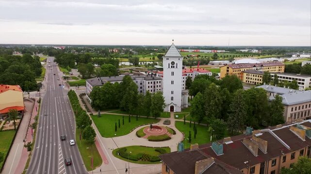 Jelgava's white tower and national monument appear beneath cloudy summer sky