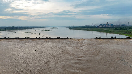 River water flowing over dam,Overflowing water in monsoon,Wide river landscape with dam,Aerial view of water reservoir, Scenic dam view at sunset stock photo.





