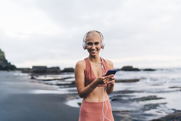 Young woman radiates joy while holding smartphone and wearing headphones, symbolizing emotional...