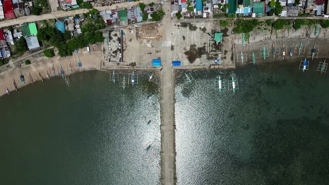 Aerial bird's eye view of traditional Filipino fishermen bangka boats docked along coastal barangay town at Codon port, Catanduanes, Philippines.