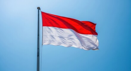 The bright red and white flag of Indonesia waves against a vibrant, cloudless blue sky, symbolizing national pride and freedom.