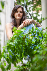 Urban Garden. A coy smile from a pretty young brunette woman in the sanctuary of an overgrown urban...