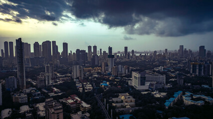 Aerial cinematic image of Mumbai during the monsoon season, featuring dramatic clouds over the city skyline. Aerial view of the Bandra-Worli Sea Link in Mumbai, India.