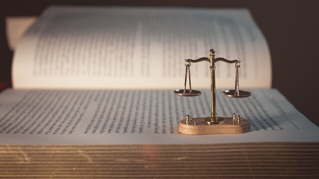Golden justice scale on open law book, symbolizing legal system, justice, balance, and education in law and ethics.