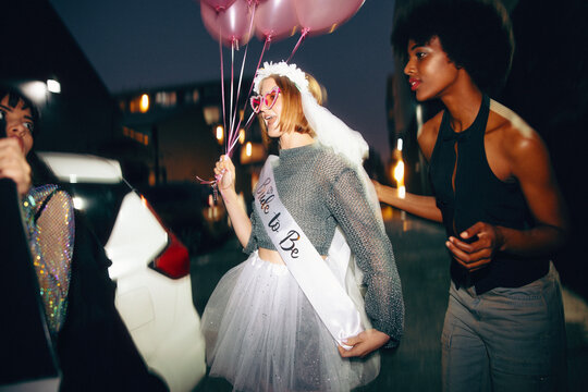Group of friends celebrating a bachelorette party at night outdoors