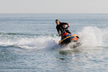 Man riding a jet ski across the water, creating splashes as he speeds over the surface.