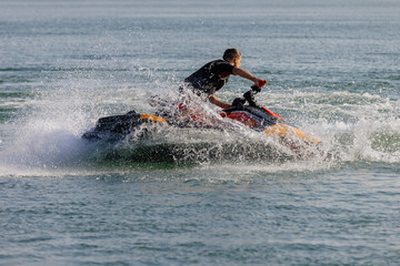 Young man speeds on a jet ski under the bright summer sun. Concept freedom, adrenaline, and water...