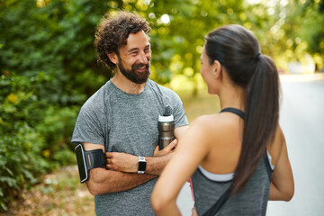Two individuals engage in a friendly conversation while enjoying a recreational walk in a lush,...