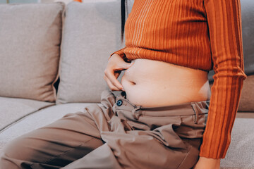 woman's hand holding excessive belly fat, overweight concept