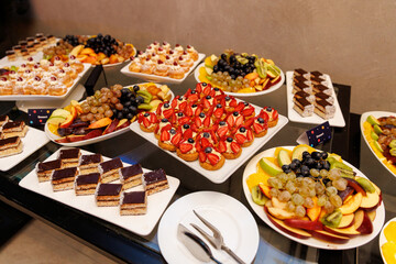 Assorted dessert platters with fruits and pastries on buffet table