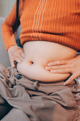 woman's hand holding excessive belly fat, overweight concept