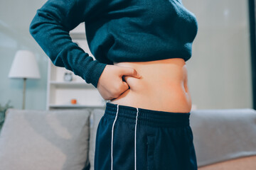woman's hand holding excessive belly fat, overweight concept