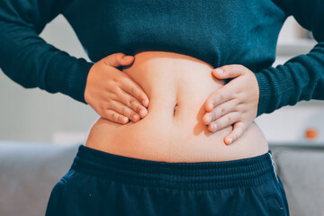 woman's hand holding excessive belly fat, overweight concept