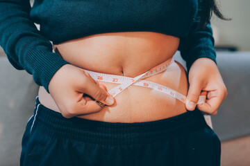 woman's hand holding excessive belly fat, overweight concept