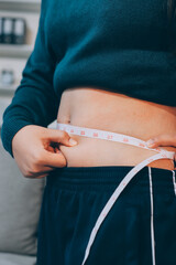 woman's hand holding excessive belly fat, overweight concept