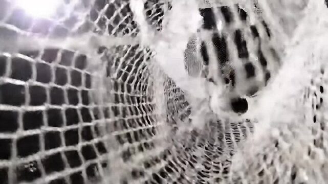 A white net against a dark background, partially illuminated by a bright light