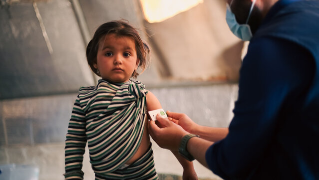 A doctor examines children's malnutrition inside a refugee camp. Malnutrition was measured using a mid-upper arm circumference belt.
