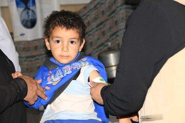 A doctor examines children's malnutrition inside a refugee camp. Malnutrition was measured using a mid-upper arm circumference belt.