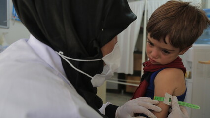 A doctor examines children's malnutrition inside a refugee camp. Malnutrition was measured using a...