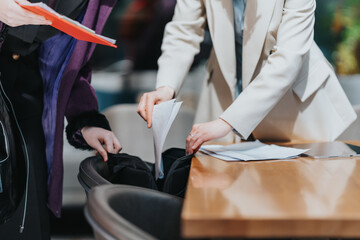Close-up of two business people collaborating to arrange paperwork at a professional setting,...