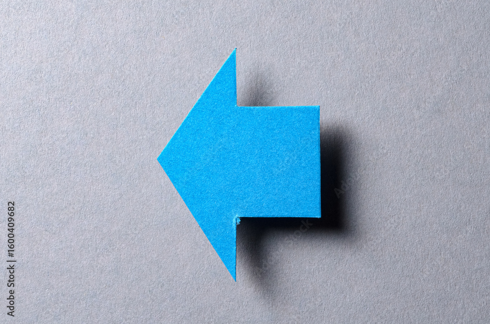 Poster Blue blank paper cardboard arrow direction sign with shadow and copy space for text on gray background, flat lay top view pointing symbol message backdrop