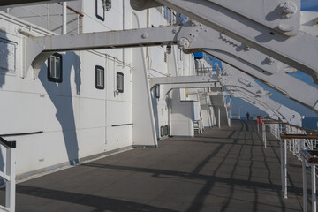 Outdoor promenade boat deck onboard historic luxury ocean liner for guests passengers with ocean views and ship´s superstructure mast and ventilation	