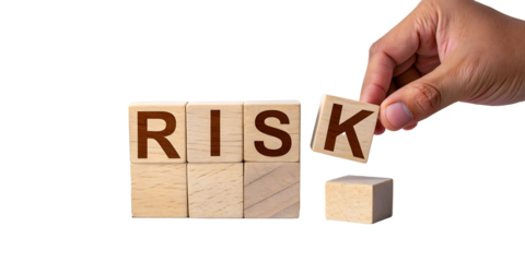 Hand placing final letter to complete the word RISK on wooden blocks, symbolizing business strategy