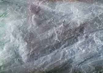 Сrumpled plastic close-up texture. Scratched glass surface. Cellophane blue abstract background. 	