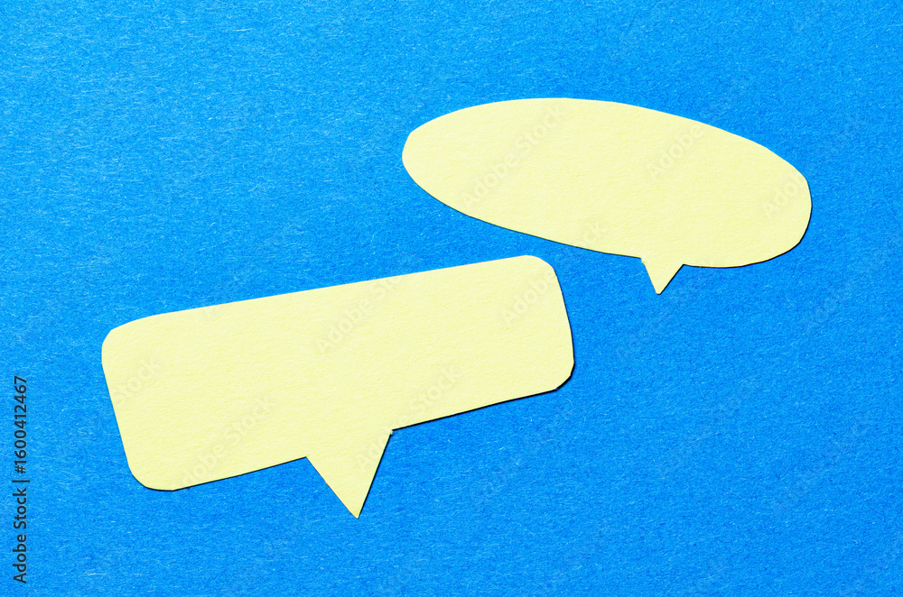 Fototapete yellow blank cut out paper speech bubbles with copy space for text on blue background, flat lay top 