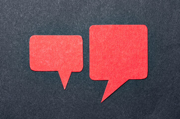 Red blank cut out paper speech bubbles with copy space for text on dark background, flat lay top...